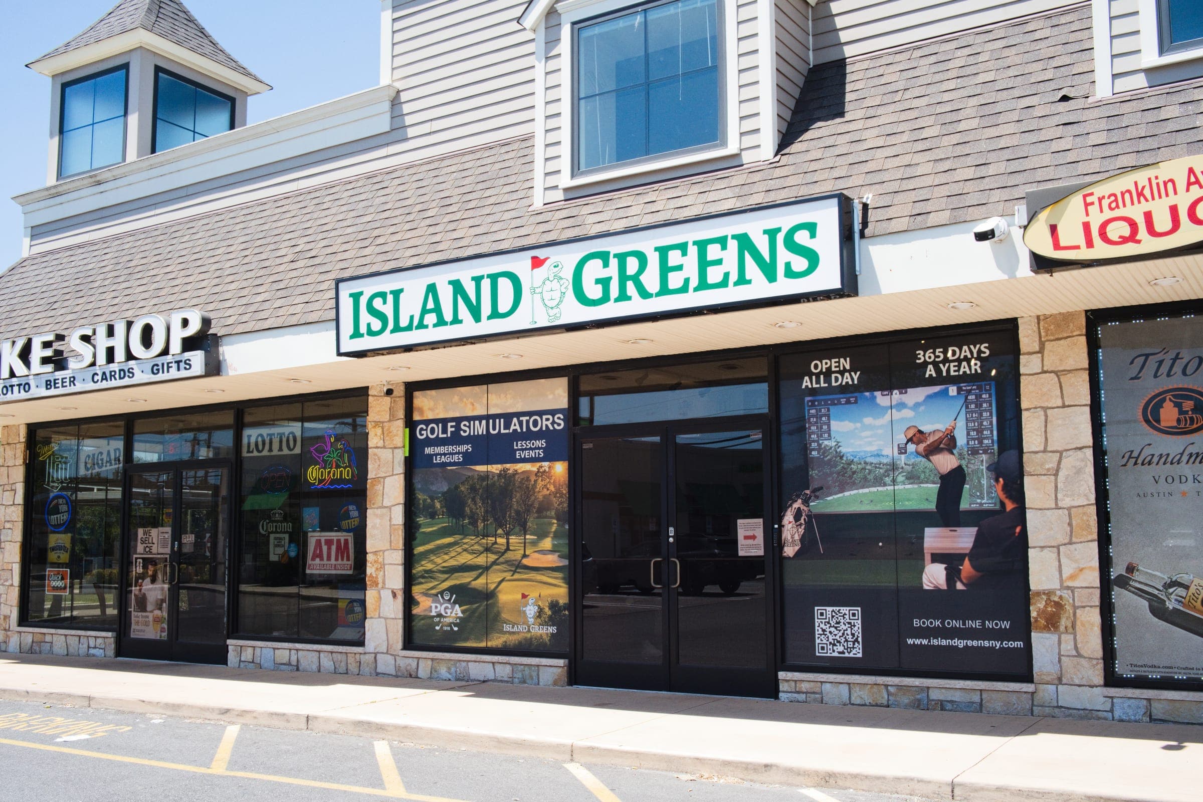 The Island Greens storefront on Franklin Avenue, its lit sign above windows advertising golf simulators.